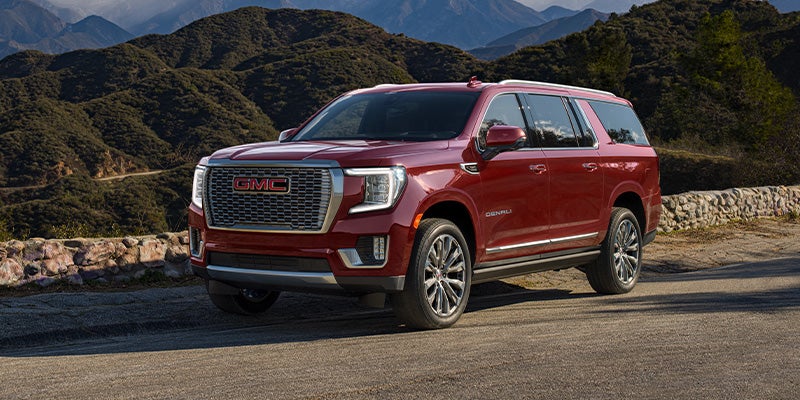 Red GMC SUV parked on a scenic mountain road with a beautiful backdrop.