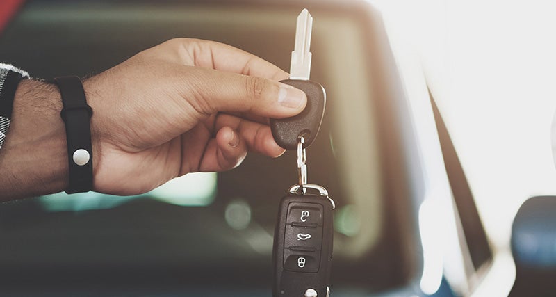 Car salesperson handing over keys to a smiling customer inside a vehicle